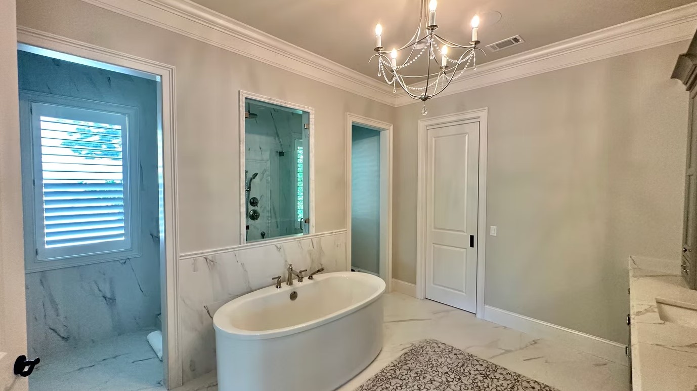 Luxury master bathroom featuring a freestanding white soaking tub, marble-tiled walls, and a large walk-in glass shower