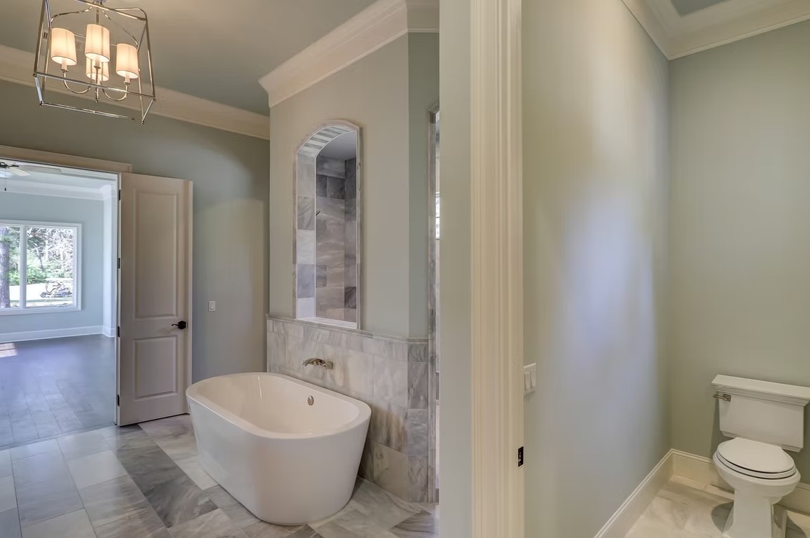 Luxury master bathroom featuring a large walk-in glass shower, marble tile walls, and a built-in stone bench.