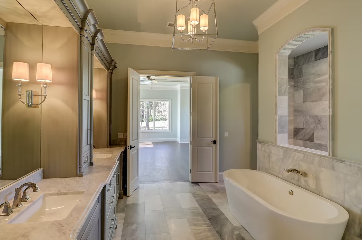 Luxury master bathroom featuring a deep freestanding soaking tub, marble-tiled walls, and high-end chrome floor-mounted fixtures.