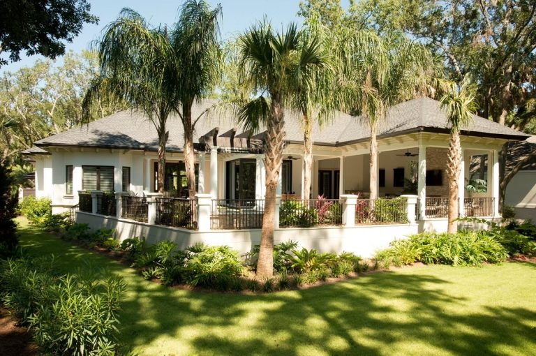 Single-story luxury home with hip roof, covered lanai, and lush tropical landscaping