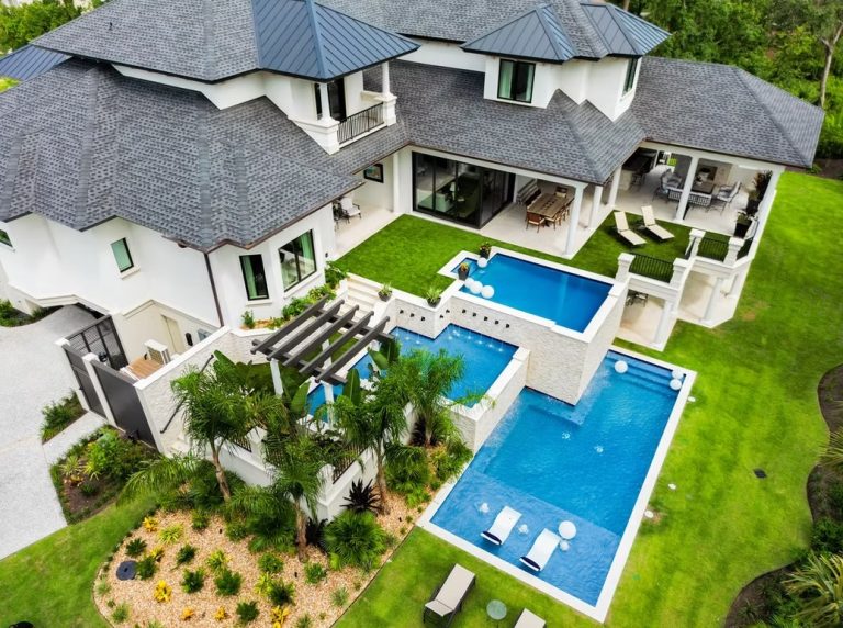 Aerial view of a resort-style backyard with pool, spa, pergola, and covered patios