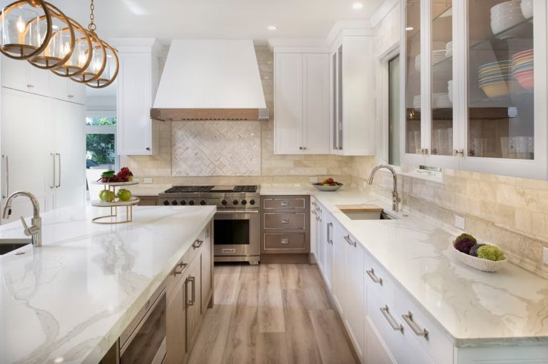 Interior view of a high-end gourmet kitchen showcasing a waterfall-edge marble island, dark wood custom cabinetry, and premium stainless steel appliances.
